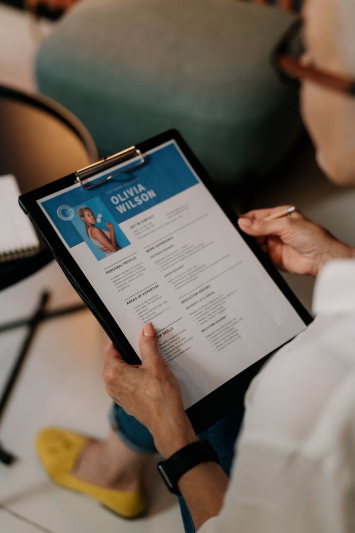 Services An HR professional reviews a resume on a clipboard during an office meeting.