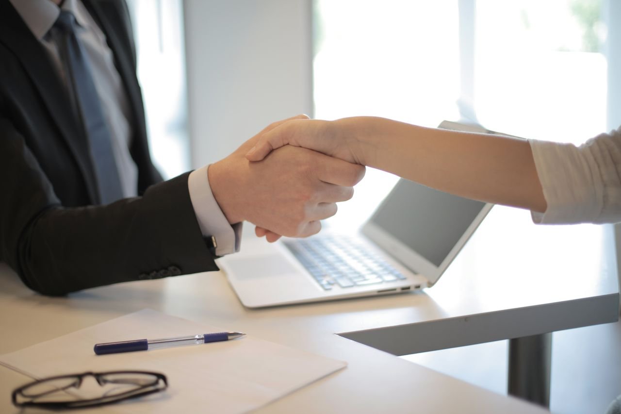 Services Close-up of a professional handshake over a laptop during a business meeting in an office.